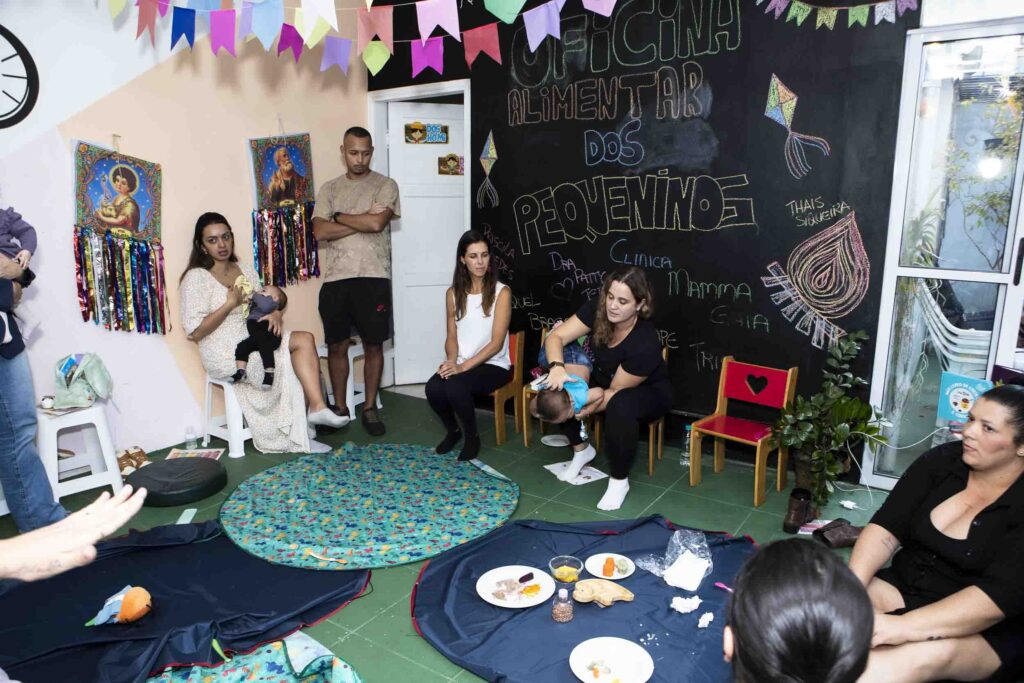 Sala da Oficina de Introdução Alimentar preparada com tapetes, pratos e lousa decorada