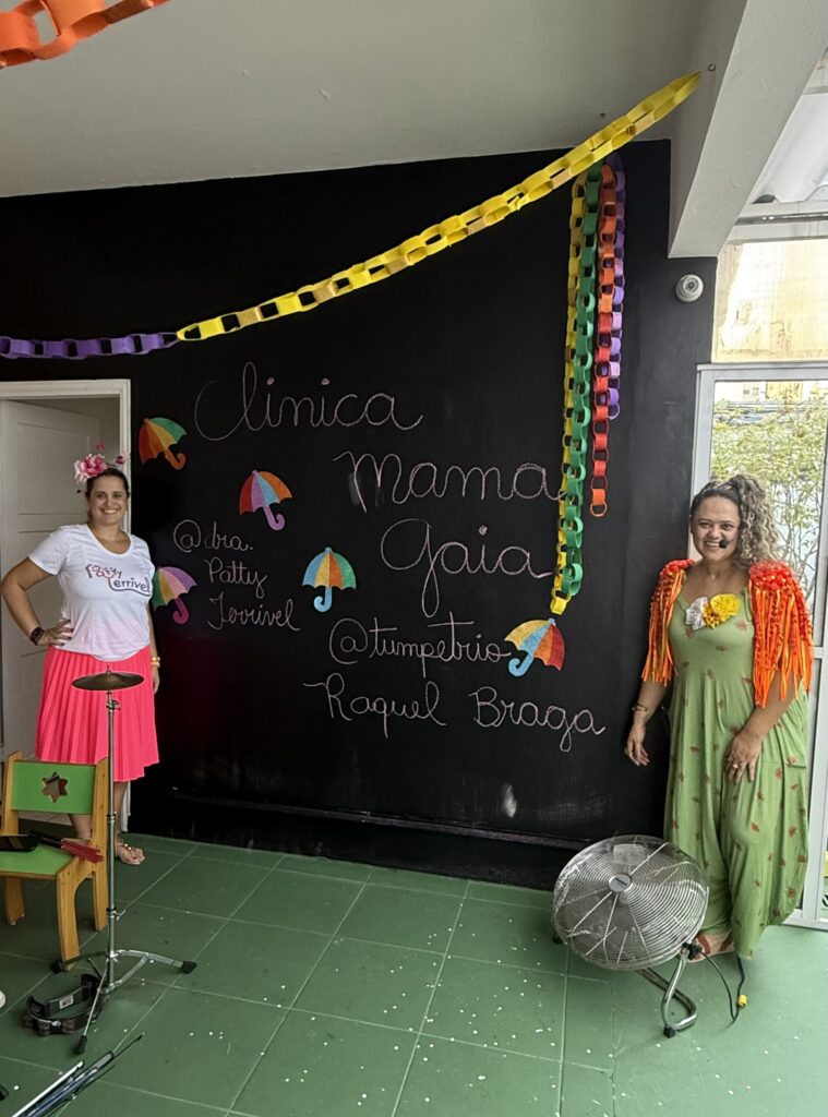 Equipe fantasiada em frente ao painel na Carnaval Gaia 2025, evento da Clínica Mamma Gaia