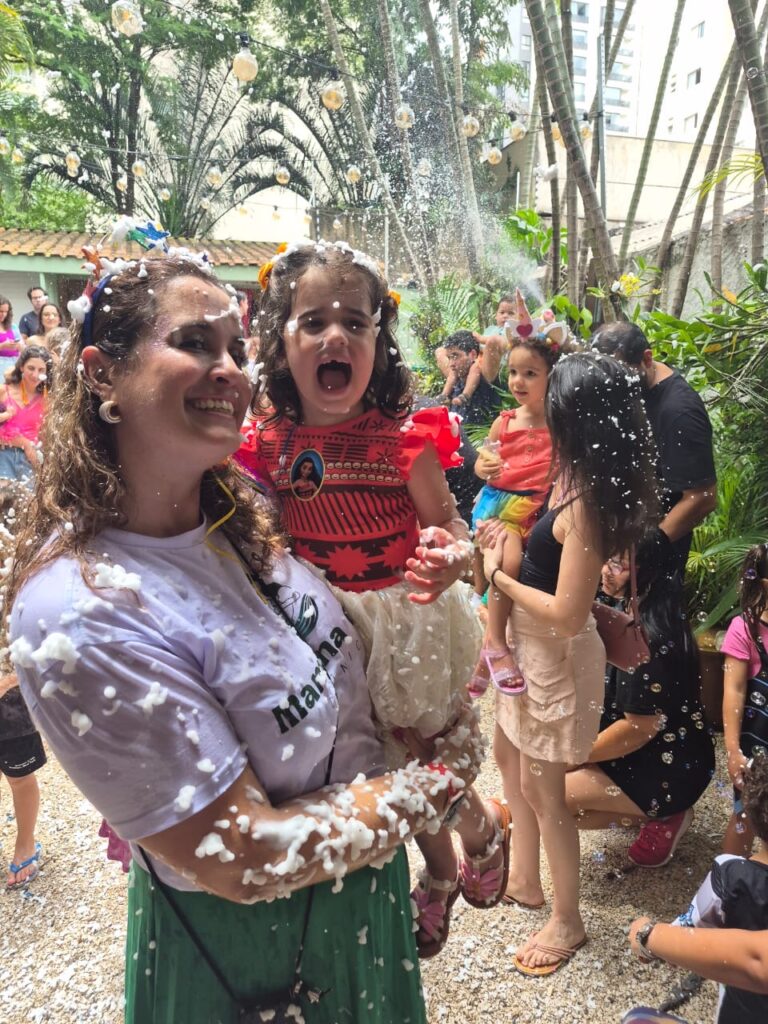 Dra. Patty com menina fantasiada entre confetes na Carnaval Gaia 2026, evento da Clínica Mamma Gaia