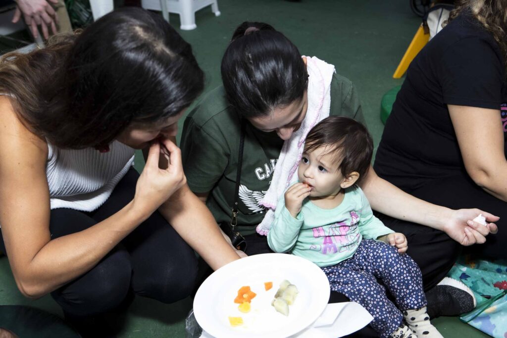 Bebê experimentando legumes cortados em pedaços na oficina de introdução alimentar