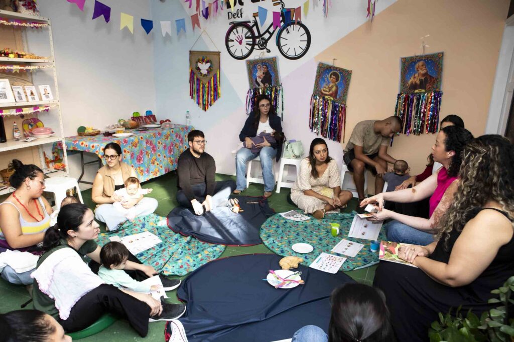 Famílias sentadas nos tapetes participando da oficina de introdução alimentar