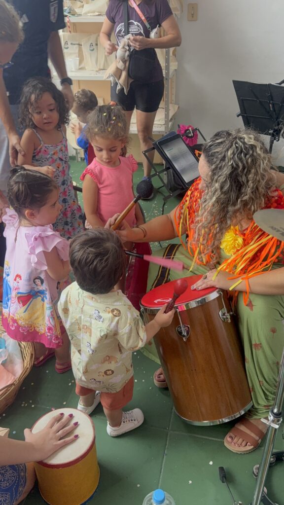 Crianças tocando tambor com a recreadora na Carnaval Gaia 2025, evento da Clínica Mamma Gaia