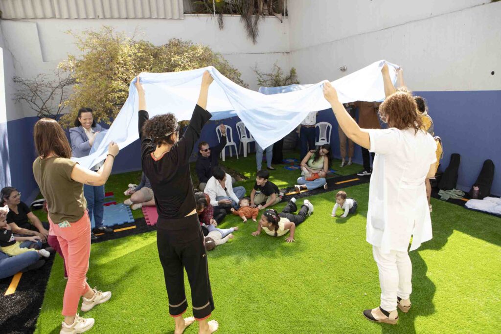 Brincadeira com tecido no gramado na Brunch com Tetê 2025, evento da Clínica Mamma Gaia