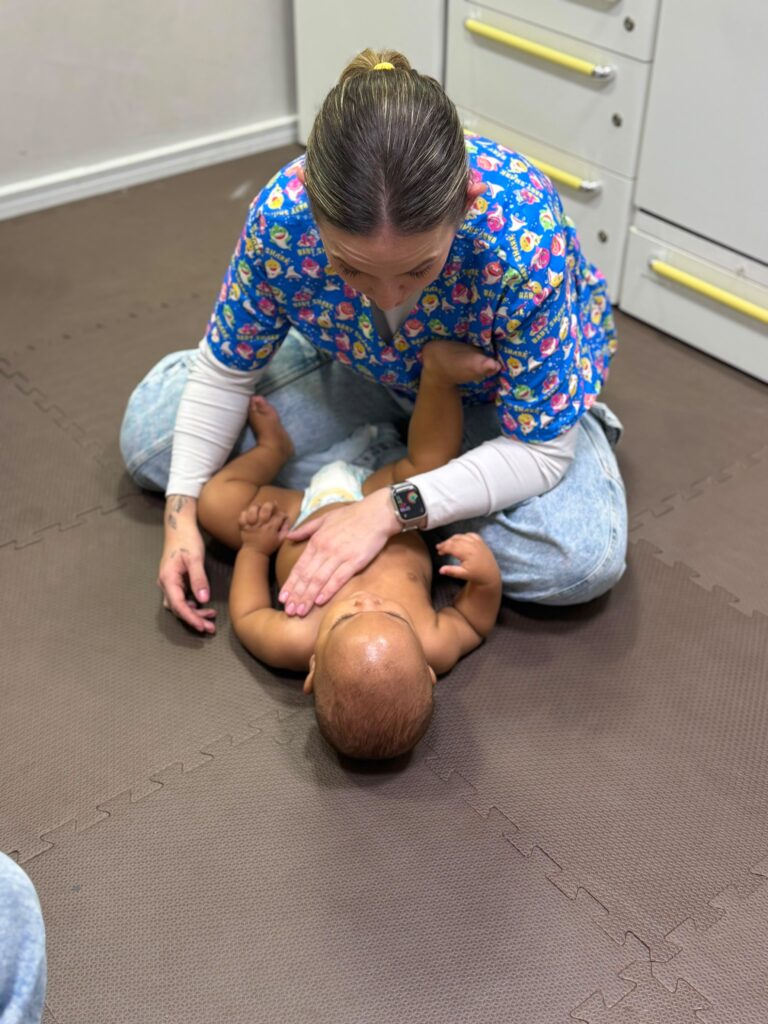 Fisioterapeuta pediátrica Stephanie realizando estimulação motora com bebê no colchonete