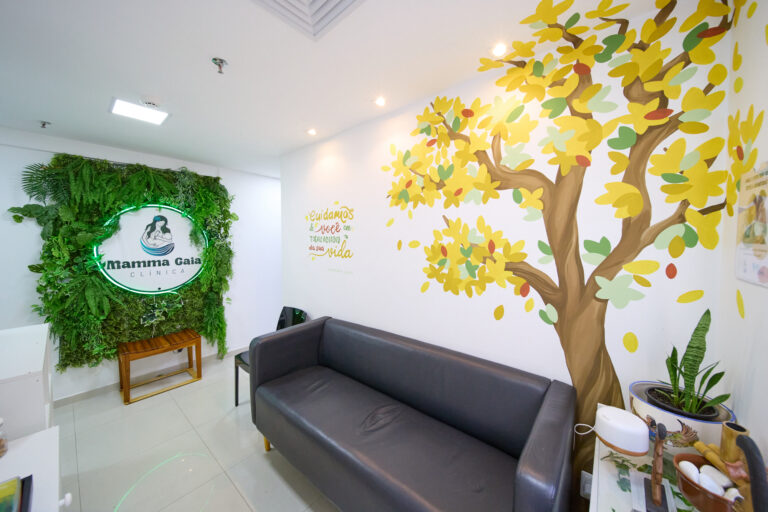Sala de espera da Clínica Mamma Gaia com parede verde viva e mural pintado da árvore da vida