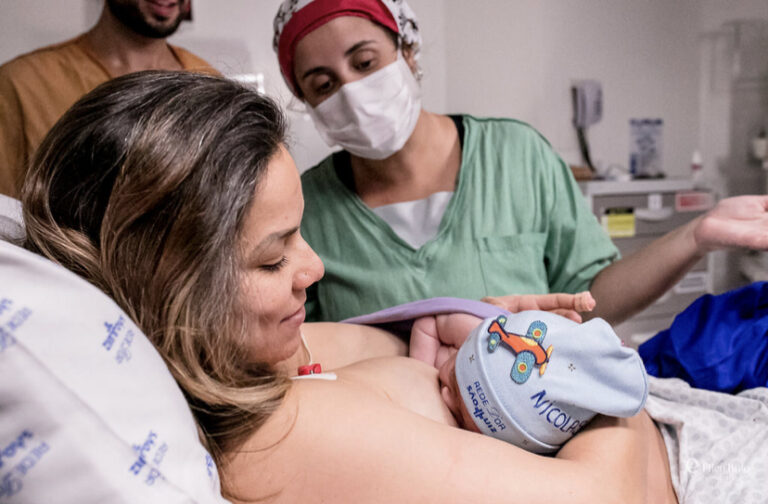 Pediatra neonatologista acompanhando o contato pele a pele da mãe com o recém-nascido na sala de parto