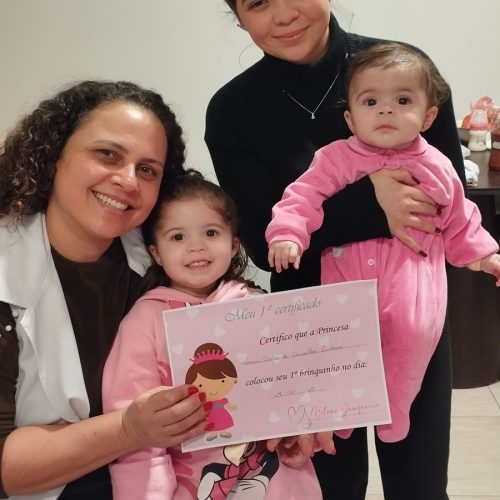 Consultora em amamentação Milene ao lado de crianças, com certificado de qualificação